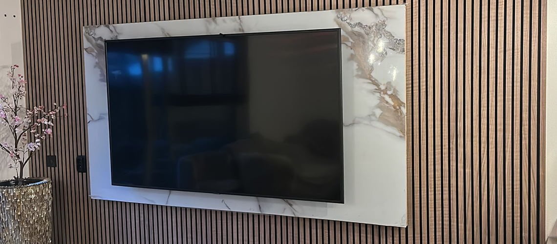 Bruine akoestische panelen met marmer platen aan een tv muur in de woonkamer
