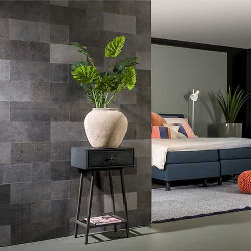 Stijlvolle slaapkamer met grijze leren wanddecoratie en plant op zwarte bijzettafel