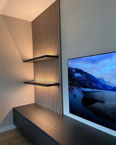 Woonkamer met houten wandpanelen en ingebouwde verlichting naast een flatscreen-tv