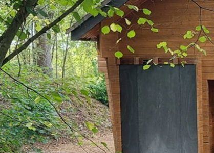 Houten schuur met zwart natuursteen detail en natuurlijke omgeving