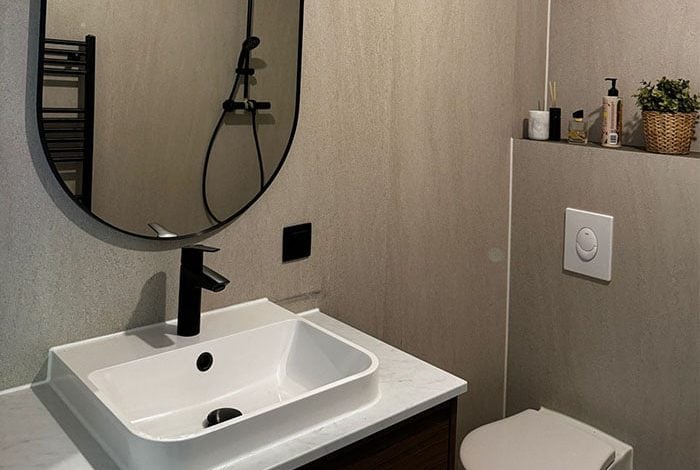 Stijlvolle badkamer met witte wastafel zwarte kraan en grijze wandtegels