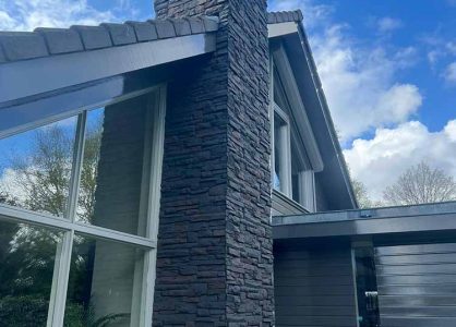 Modern huis met 3d wandpanelen gevelbekleding aan schoorsteen en grote ramen