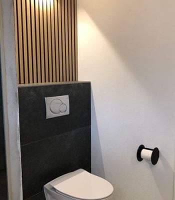 Trap met houtstrips en glazen balustrade tegen een stenen muur