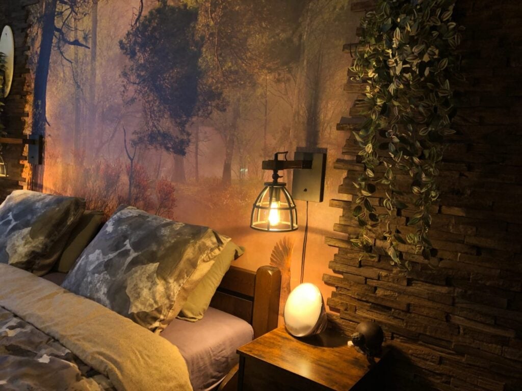 Slaapkamer met industriële bosmuur, houten bed, lamp en planten
