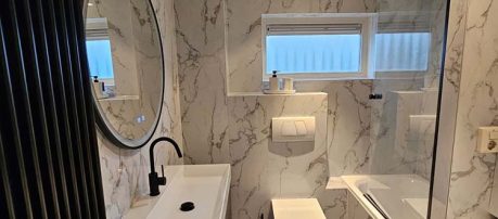 Badkamer met marmerlook wandbekleding en moderne wastafel