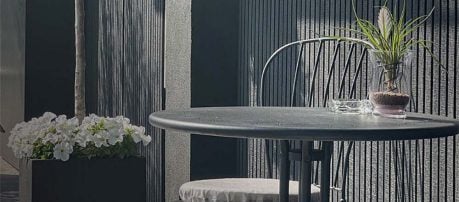 Buitenterras met verticale kunststof gevelbekleding en plant
