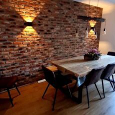 Eetkamer met industriële bakstenen muur, houten tafel en stoelen