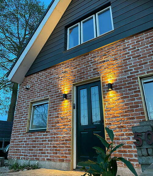 Huis gevelbekleding bij schemering met verlichte lampen en bakstenen