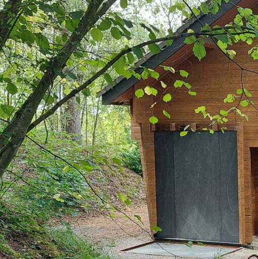Houten hut in bos met natuursteen gevelbekleding en natuurlijk pad