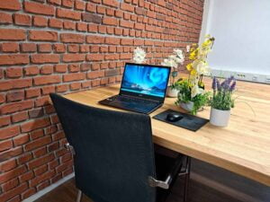 Thuiswerkplek met laptop op een bureau, versierd met planten en een bakstenen muur als achtergrond