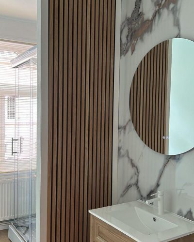 Badkamer met marmeren muur houten accenten en ronde spiegel romantisch interieur
