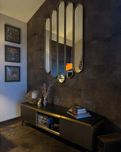 Woonkamer met industriële donkere muur, decoratieve spiegel en kast