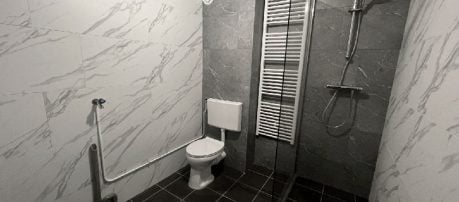 Badkamer met toegankelijke voorzieningen zoals grijze zelfklevende tegel wandbekleding en douche